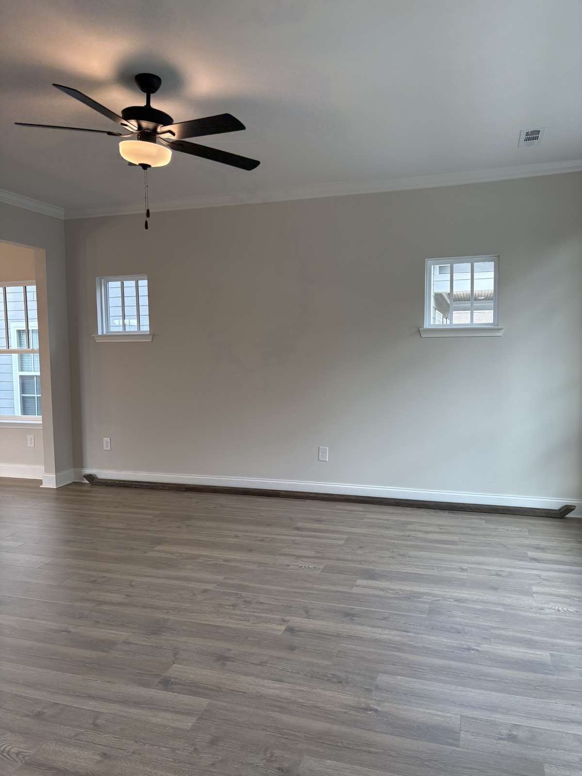 Large family room with crown molding, laminate flooring and gas burning fireplace.