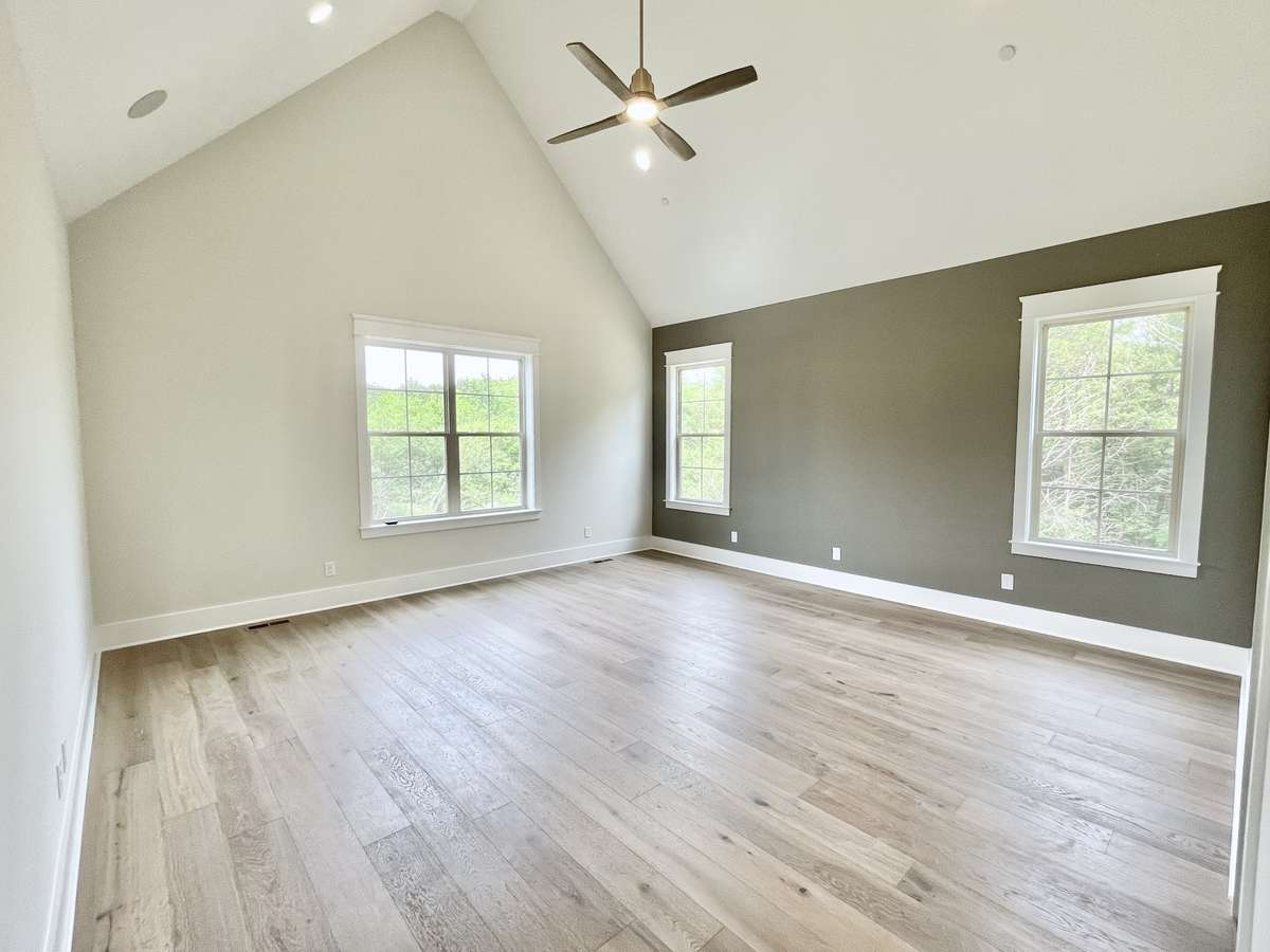 Elegant primary bedroom with dramatic vaulted ceiling, stunning hardwood floors and 8' tall solid-core doors!