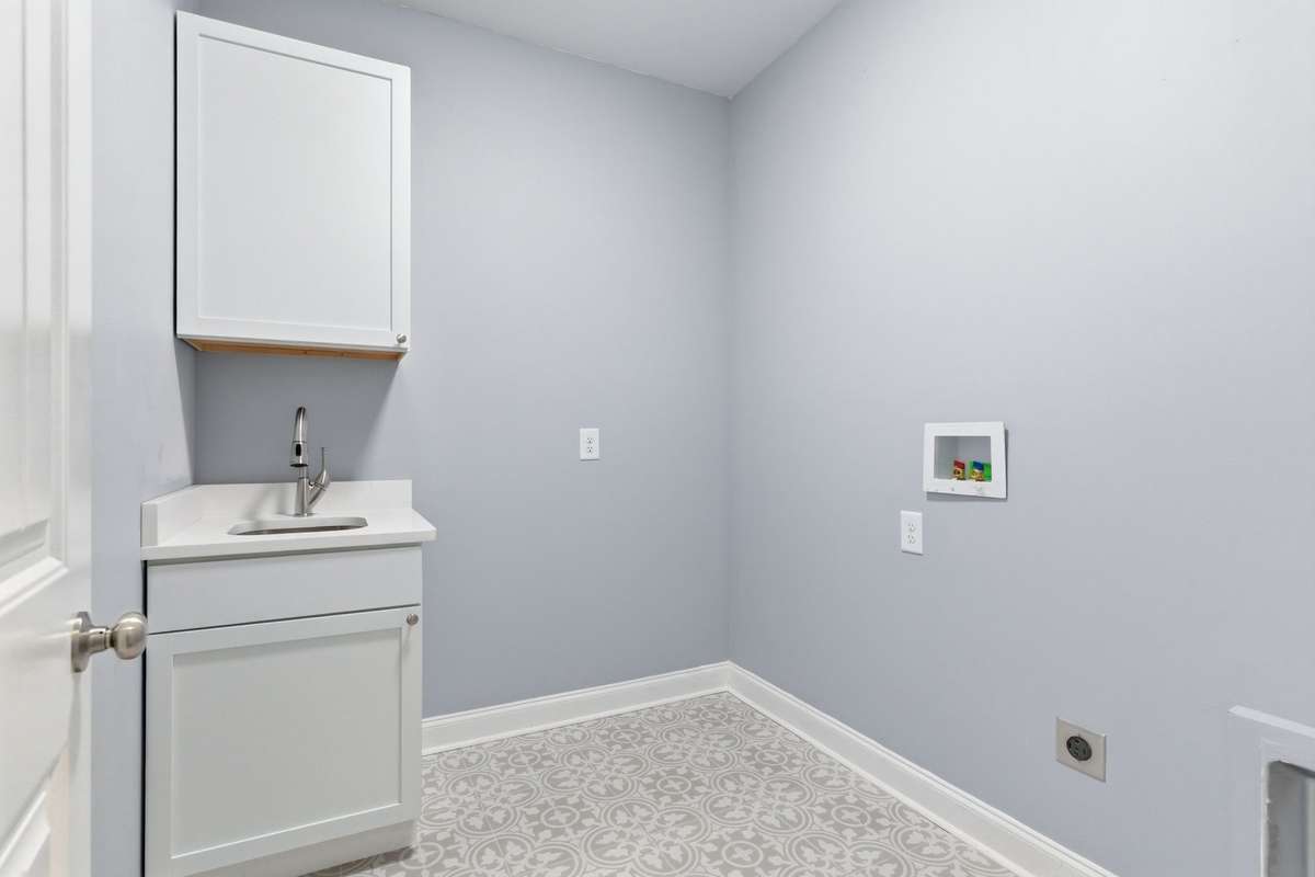 Spacious Laundry Room Complete with Sink in Vanity and Overhead Storage Cabinet