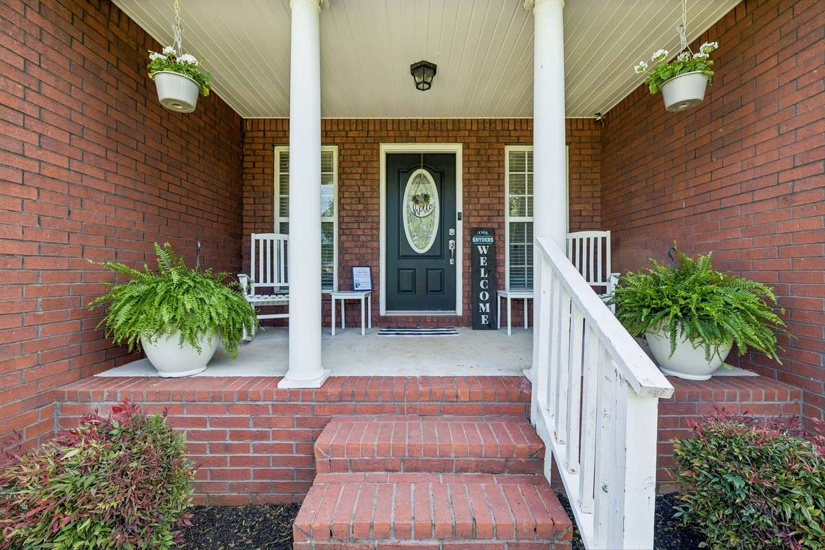 Covered front porch with brick steps and a warm, inviting entry.