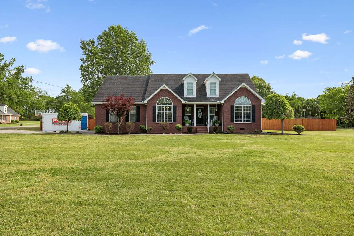 Straight-on exterior view showcasing arched windows and timeless charm, with a concrete driveway. Moving Pod in driveway...