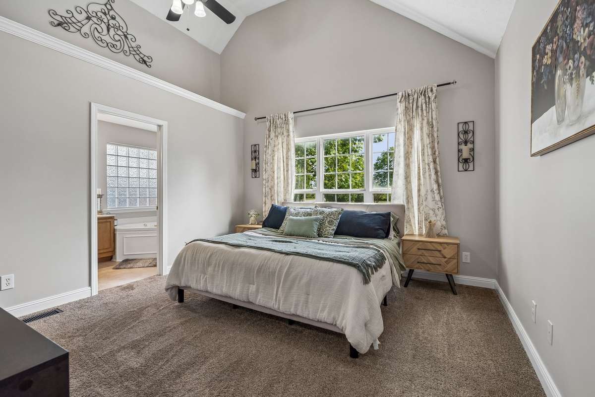 Spacious master bedroom with vaulted ceiling and attached bath access.
