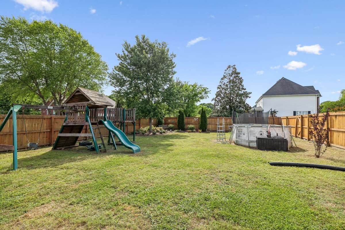 Backyard features above-ground pool, playset, and room to enjoy.