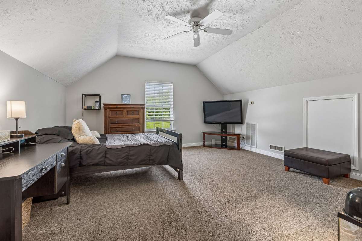 Upstairs bedroom or bonus room with vaulted ceiling and flexible space.