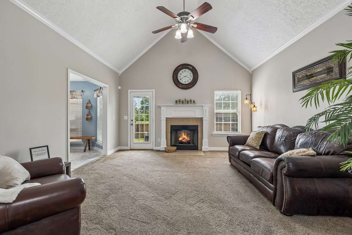 Vaulted living room featuring a cozy fireplace and backyard access.