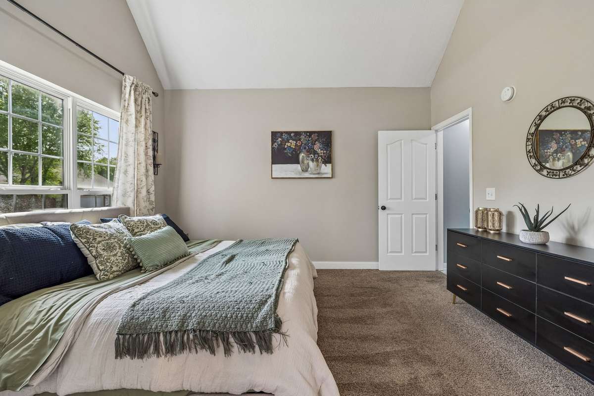 Bedroom view with large window and neutral finishes.