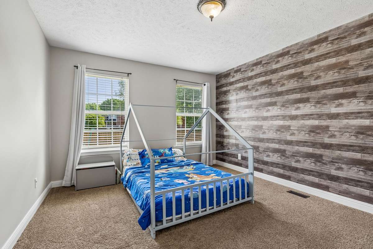 Additional third bedroom with two windows and wood-look accent wall.