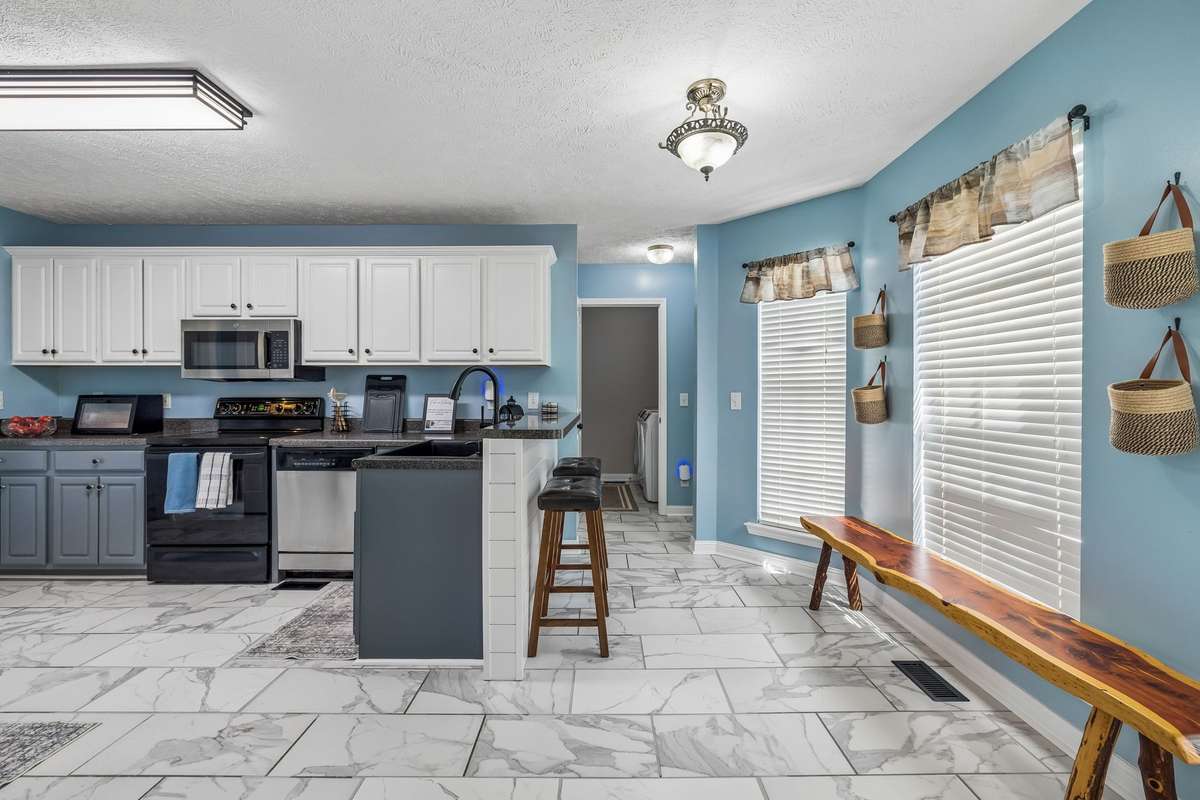 Kitchen with white upper cabinetry, gray lower cabinets, and tile flooring.
