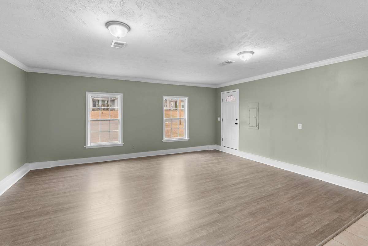 The bonus room features a combination of tile and luxury vinyl flooring, along with two large windows with views of the front yard.