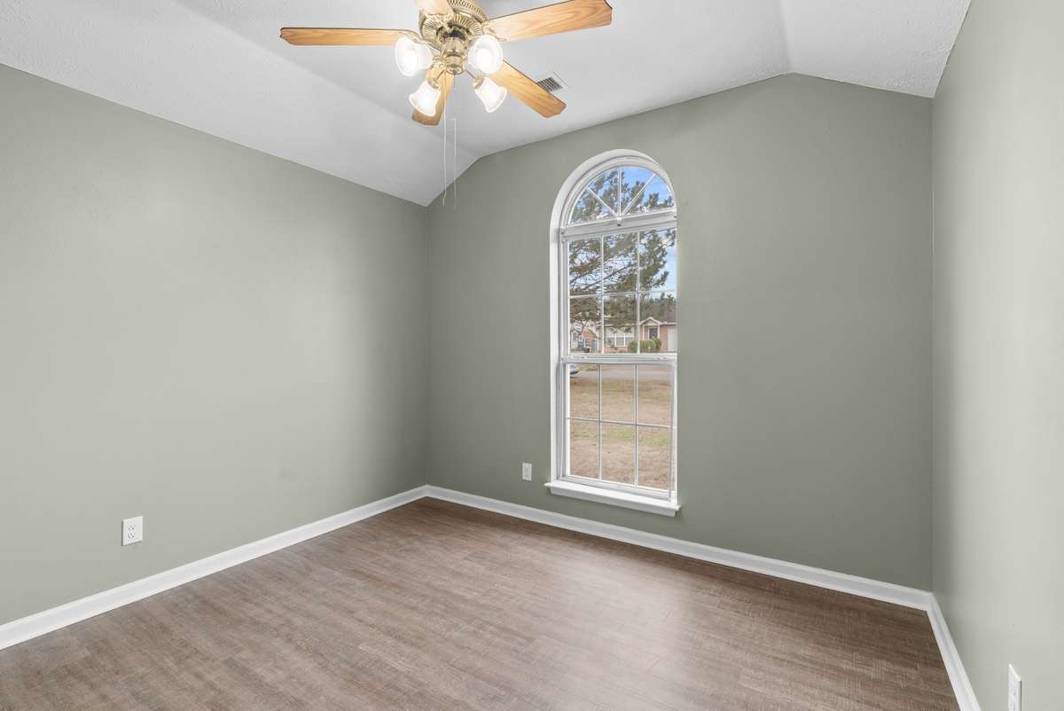 Bedroom two boasts an impressive vaulted ceiling, luxury vinyl flooring, a full closet, and a bright window crowned by a Palladian window that adds architectural elegance.