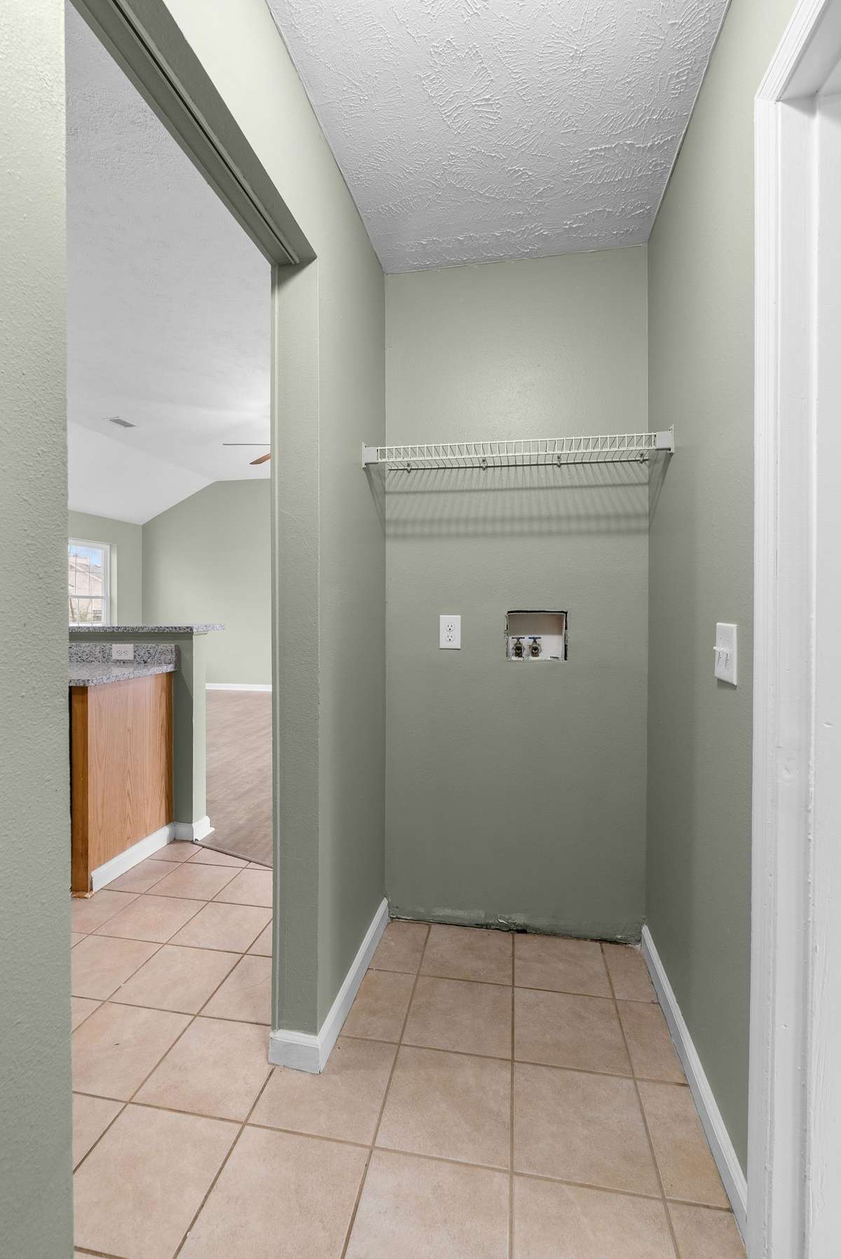A thoughtfully designed walk-through laundry area offers built-in shelving, creating an organized and efficient space for daily living.