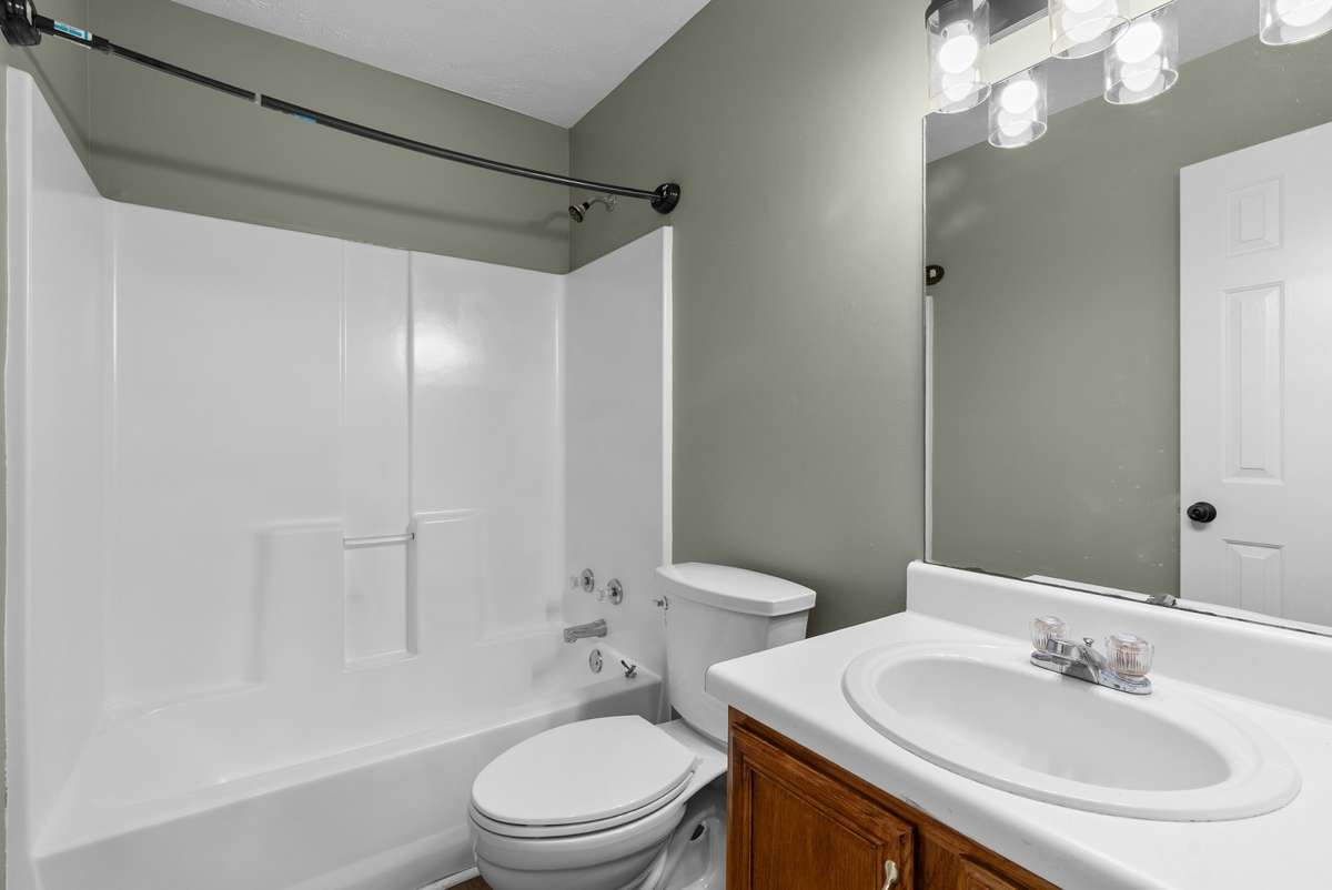 The hall bath includes luxury vinyl flooring, a tub/shower combination, chrome fixtures, a chic
matte black light fixture, and warm wood cabinetry—offering a polished and modern feel.