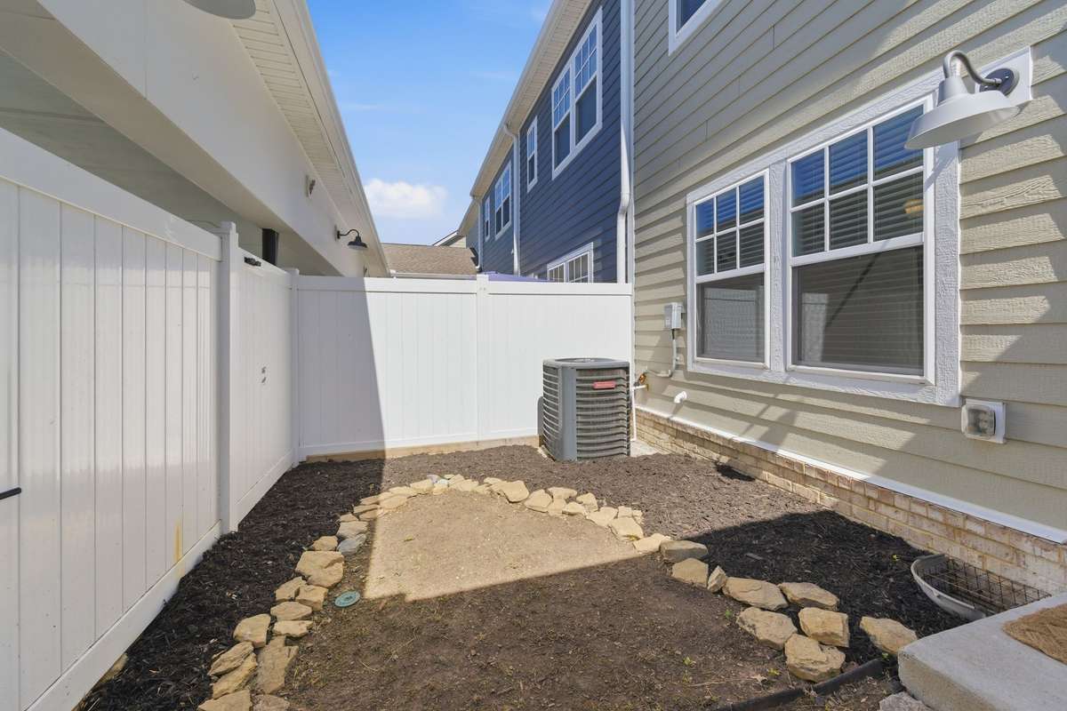 Private, fenced-in space with stone walkway connects the home to the carport. The area was recently cleared and new mulch laid to set the new owners up with full customization options.