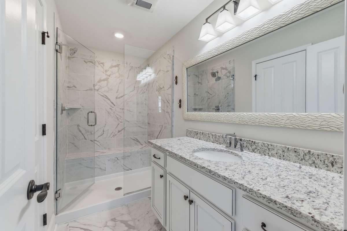 Elegant primary bathroom with step-in, frameless shower and water closet for privacy.