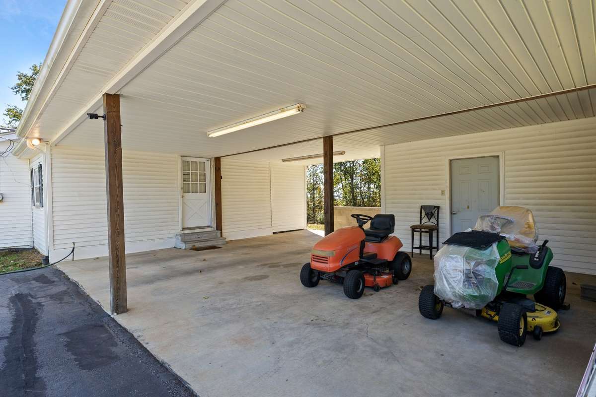 2 car attached carport with concrete parking area and enclosed storage room