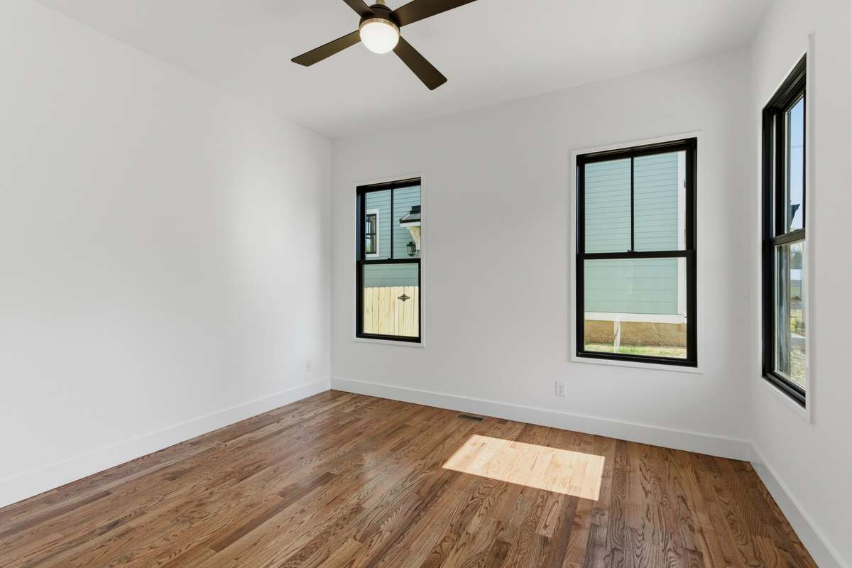The main floor includes a bright guest bedroom with large windows and beautiful walnut hardwoods.