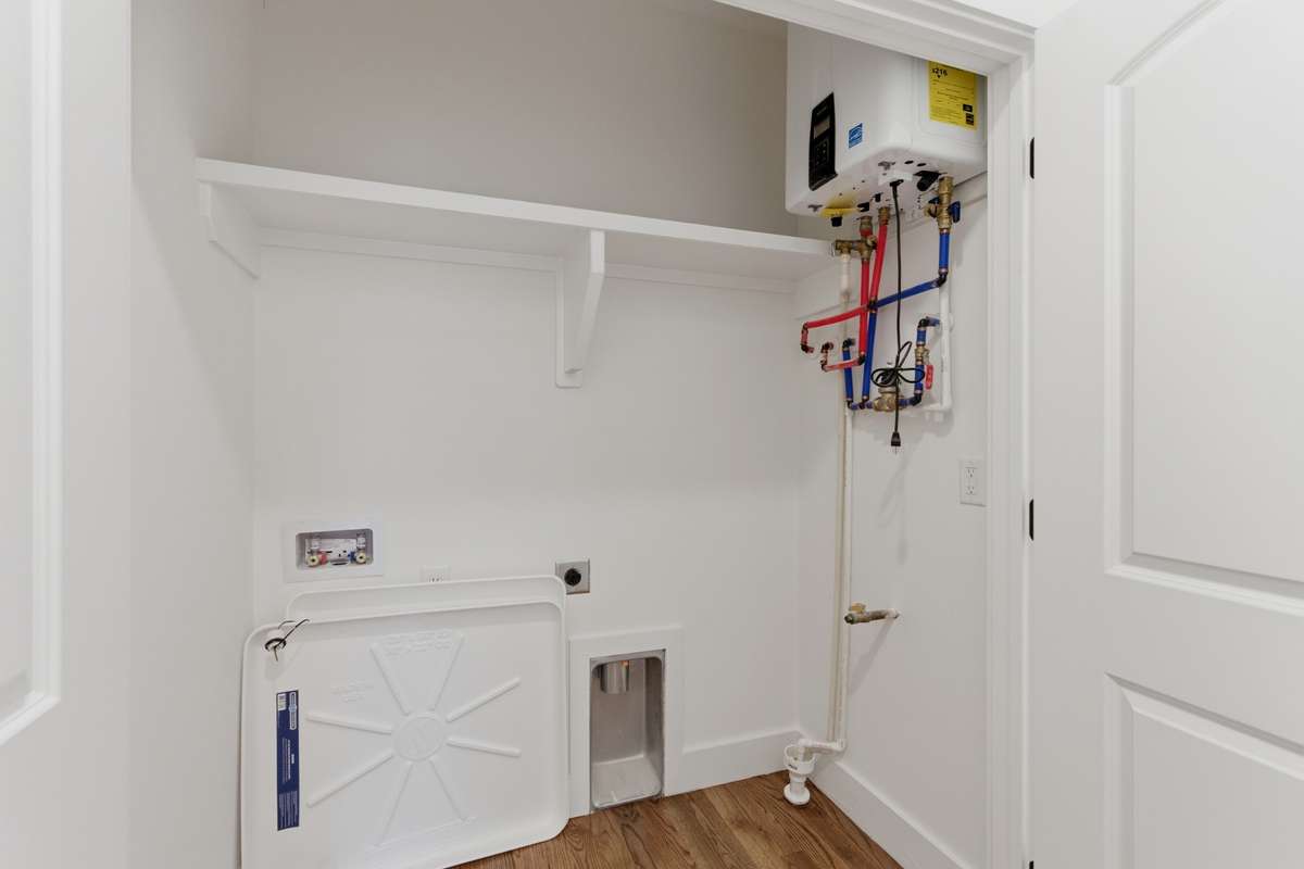 The laundry room is conveniently located on the second floor near the bedrooms and features a tankless water heater, extra shelving, and plenty of space for a full-size side-by-side washer and dryer.
