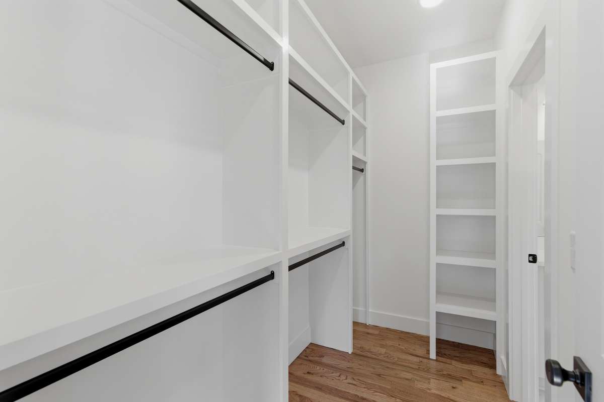 This walk-in closet features custom built-in shelving and dual entryways, allowing you to enter conveniently from either the primary bathroom or the hallway.