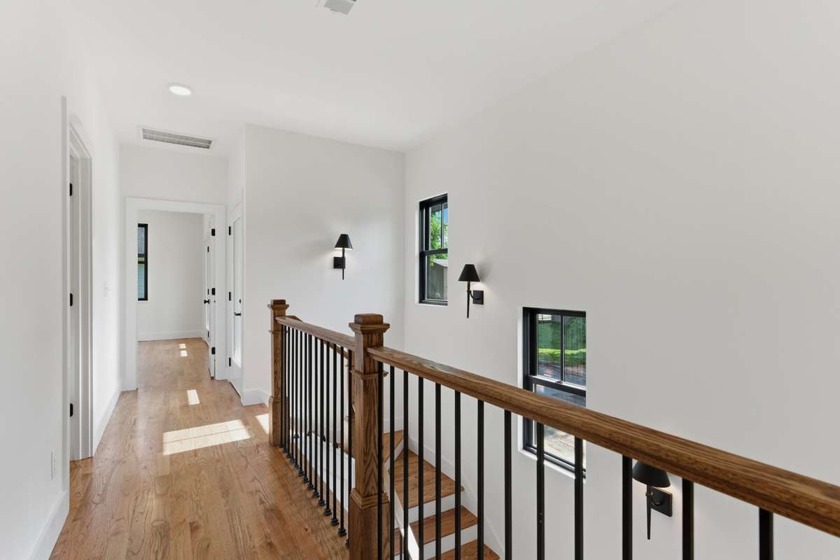 The upstairs landing feels open and bright, featuring modern black sconces that add a clean, high-end look to the hallway.