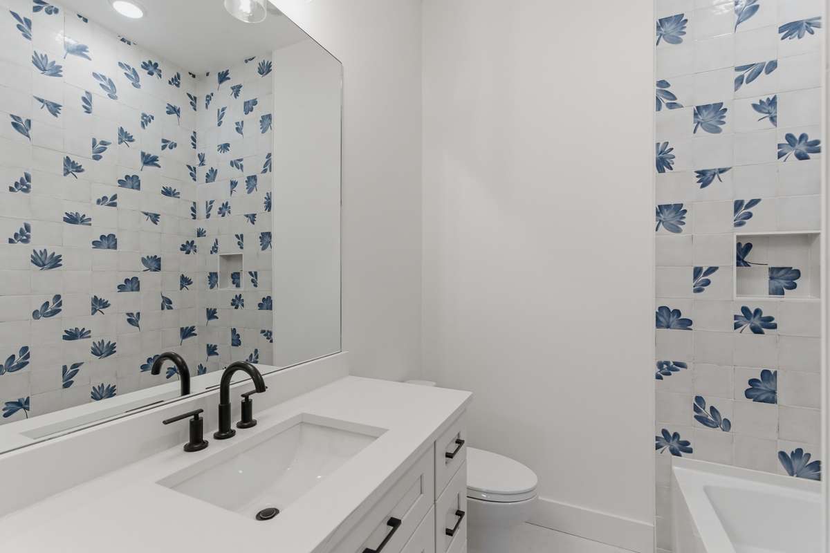 The guest bathroom is conveniently located right in the hallway and features a clean white vanity with quartz countertops.