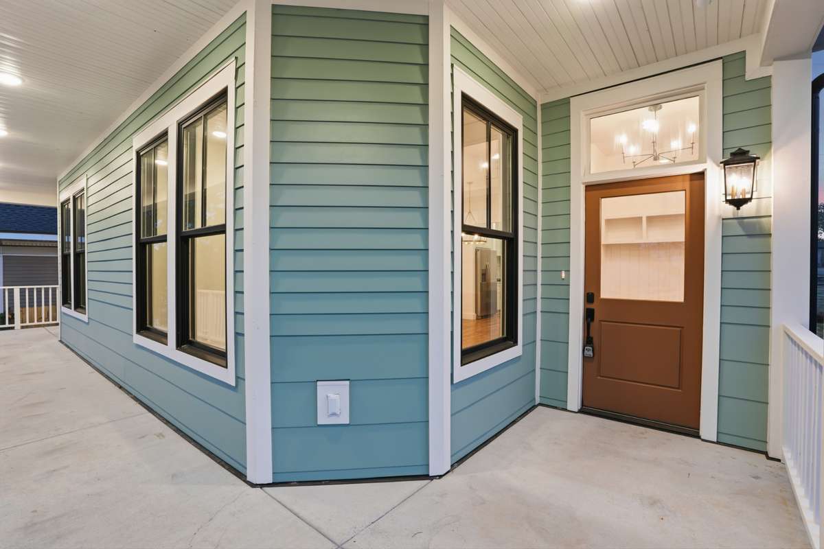 The entrance features a warm wood-toned door paired with a modern black lantern and clean white trim.