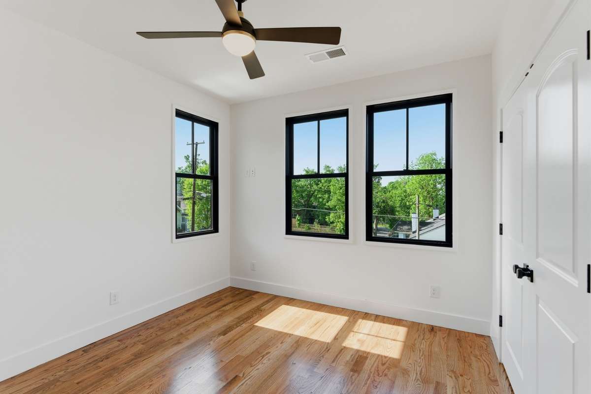 Large black-frame windows in the third bedroom provide great views of the neighborhood and plenty of natural light.