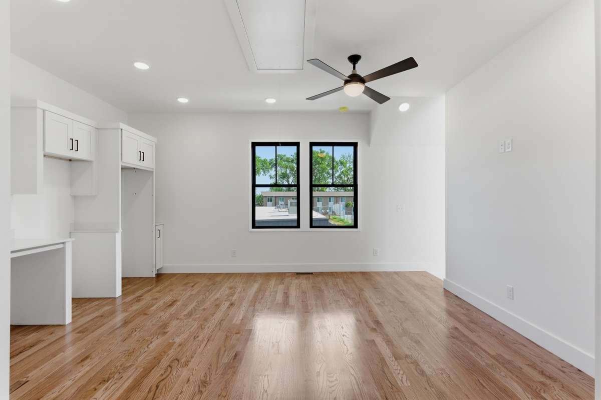 This open-concept living area feels bright and airy, complete with beautiful walnut hardwoods and a modern ceiling fan.