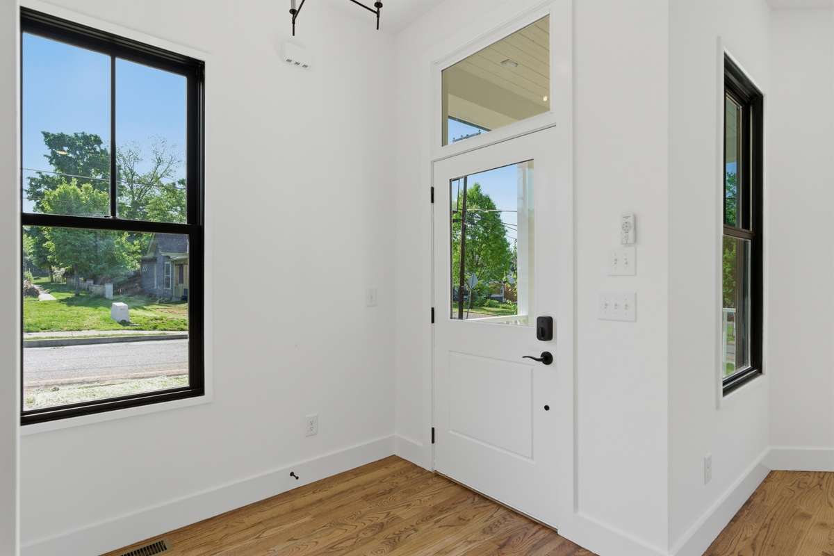 Natural light floods the entryway through large windows and a glass-paneled front door.