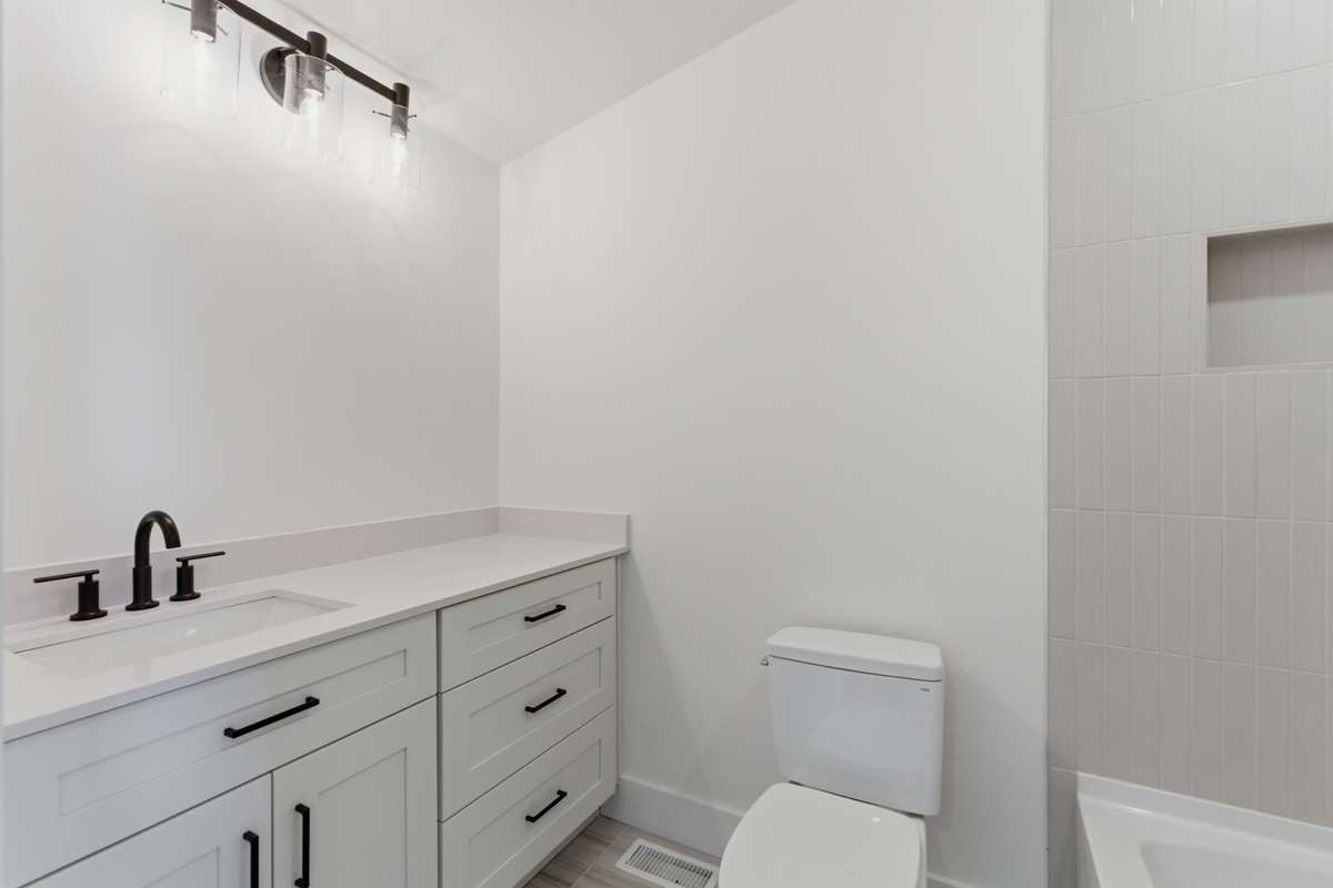 The DADU bathroom features a clean white vanity with quartz counters and sleek black hardware to match the home's high-end finishes.