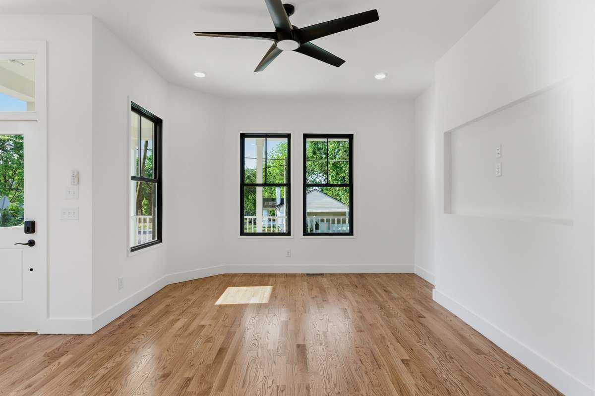 The spacious living room features a recessed niche for a flush-mounted TV, while large windows fill the space with natural light.