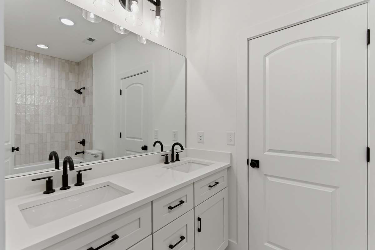 The shared upstairs bath is designed for efficiency with a double vanity, quartz countertops, and clean white cabinetry.