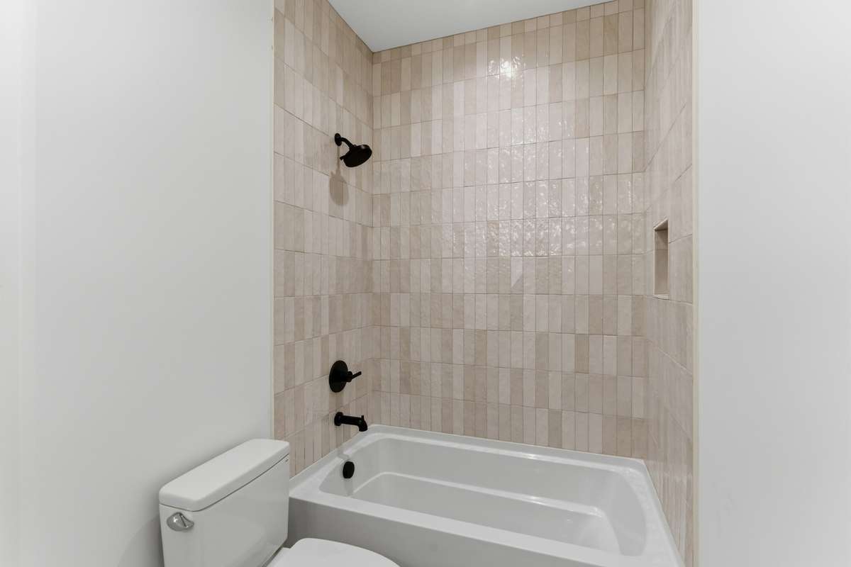 Floor-to-ceiling zellige-style tile surrounds the tub, paired with modern black fixtures for a high-end look.