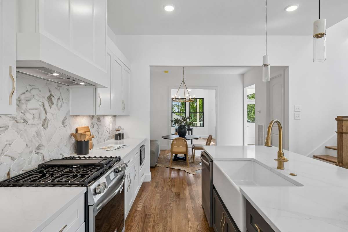 A marble backsplash frames the stainless gas range and custom hood.