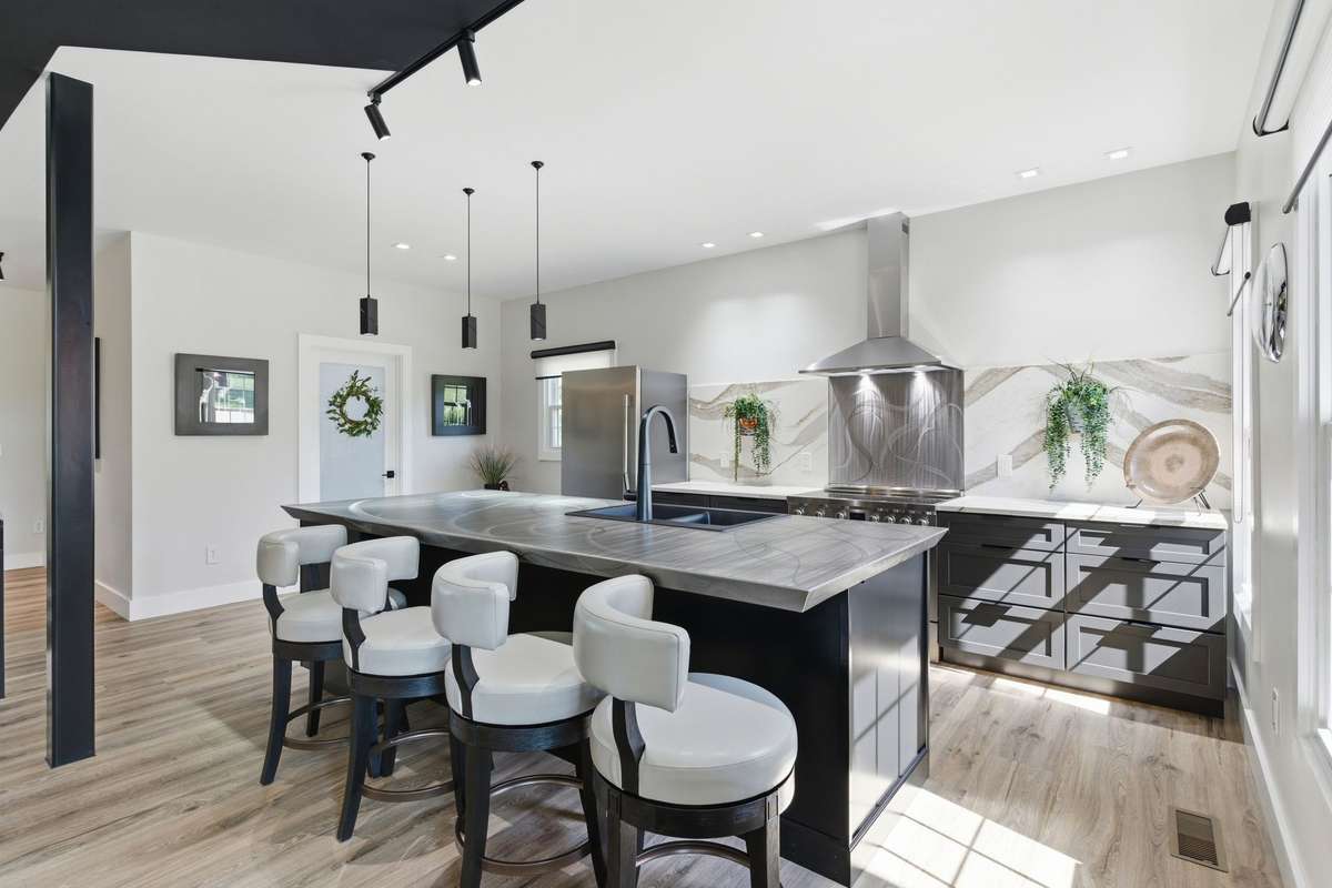 Gorgeous kitchen featuring large island with bar, quartz countertops and backsplash, stainless steel appliances. You will love this designer island top- brushed steel!