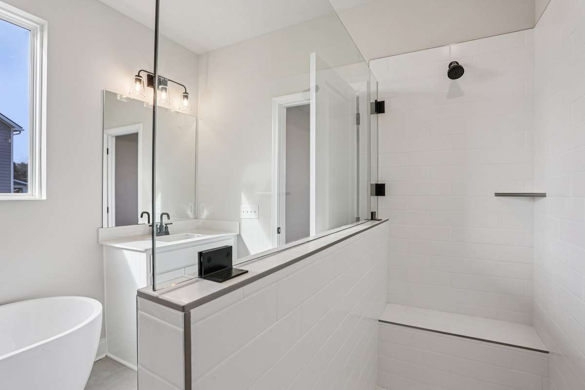 Luxurious oversized walk-in shower featuring sleek frameless glass, creating a modern, open concept feel. Beautifully tiled, this spa-inspired retreat offers ample space and a seamless, elegant design.