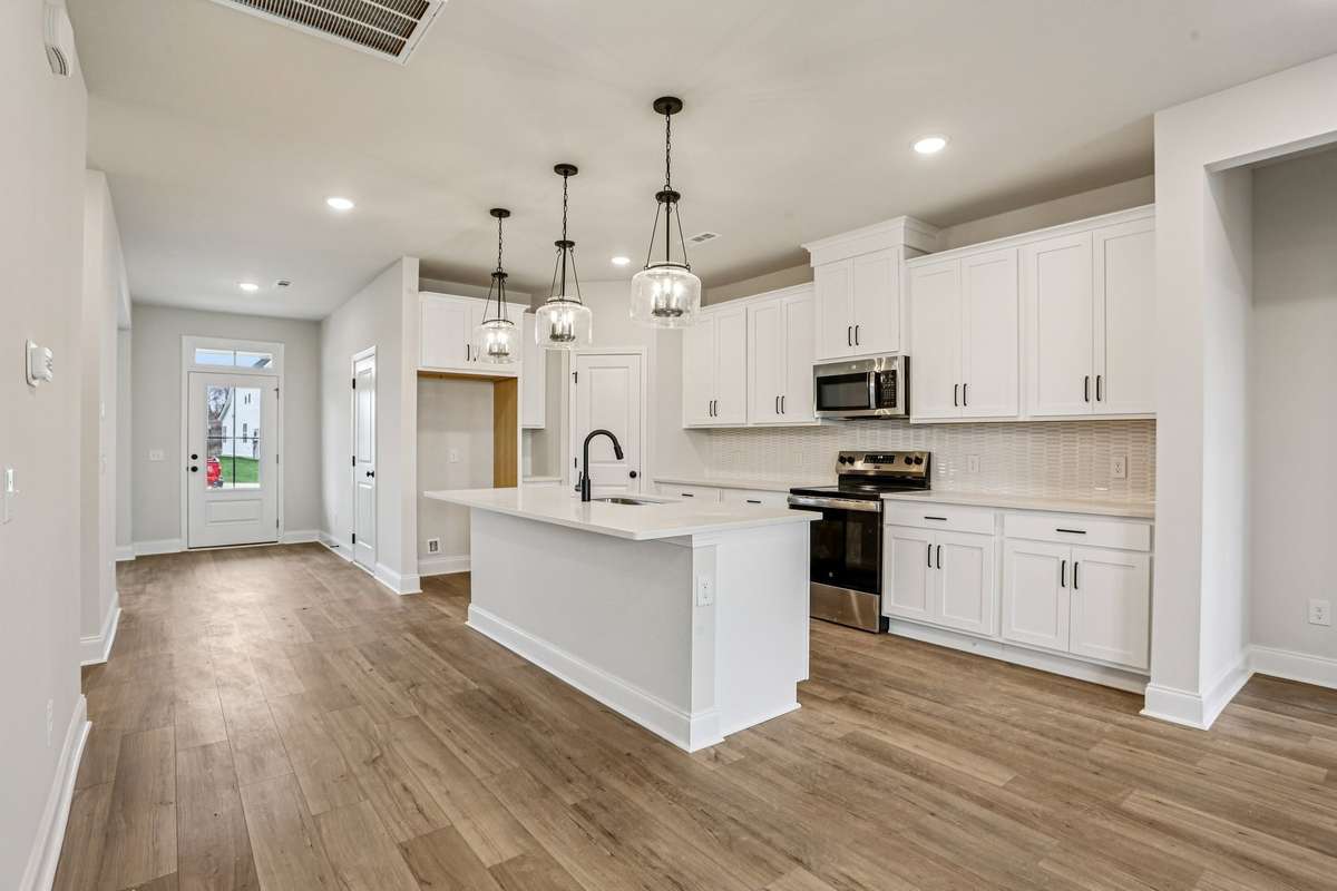 The kitchen includes white cabinetry, quartz countertops, pendant lighting and stainless-steel appliances.