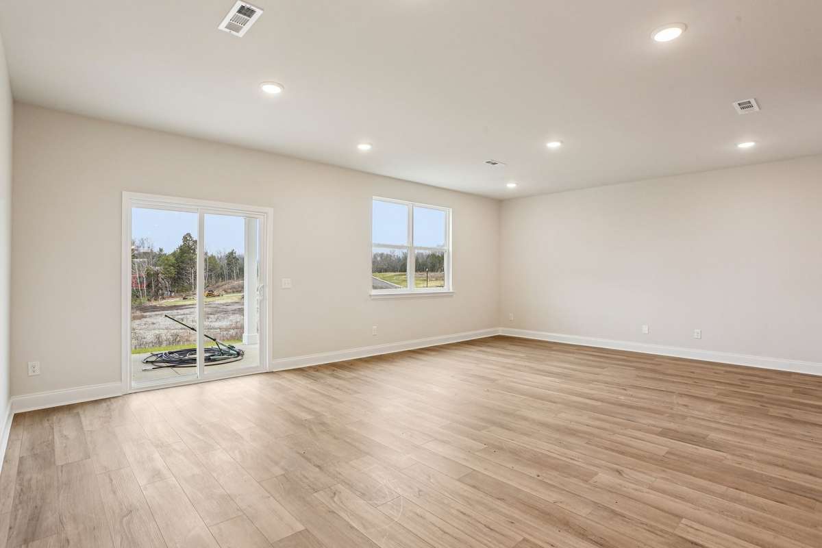 Stunning great room bathed in natural light, showcasing expansive windows that frame breathtaking views. The open layout seamlessly connects living, dining, and entertaining spaces—perfect for relaxing or hosting with a view.
