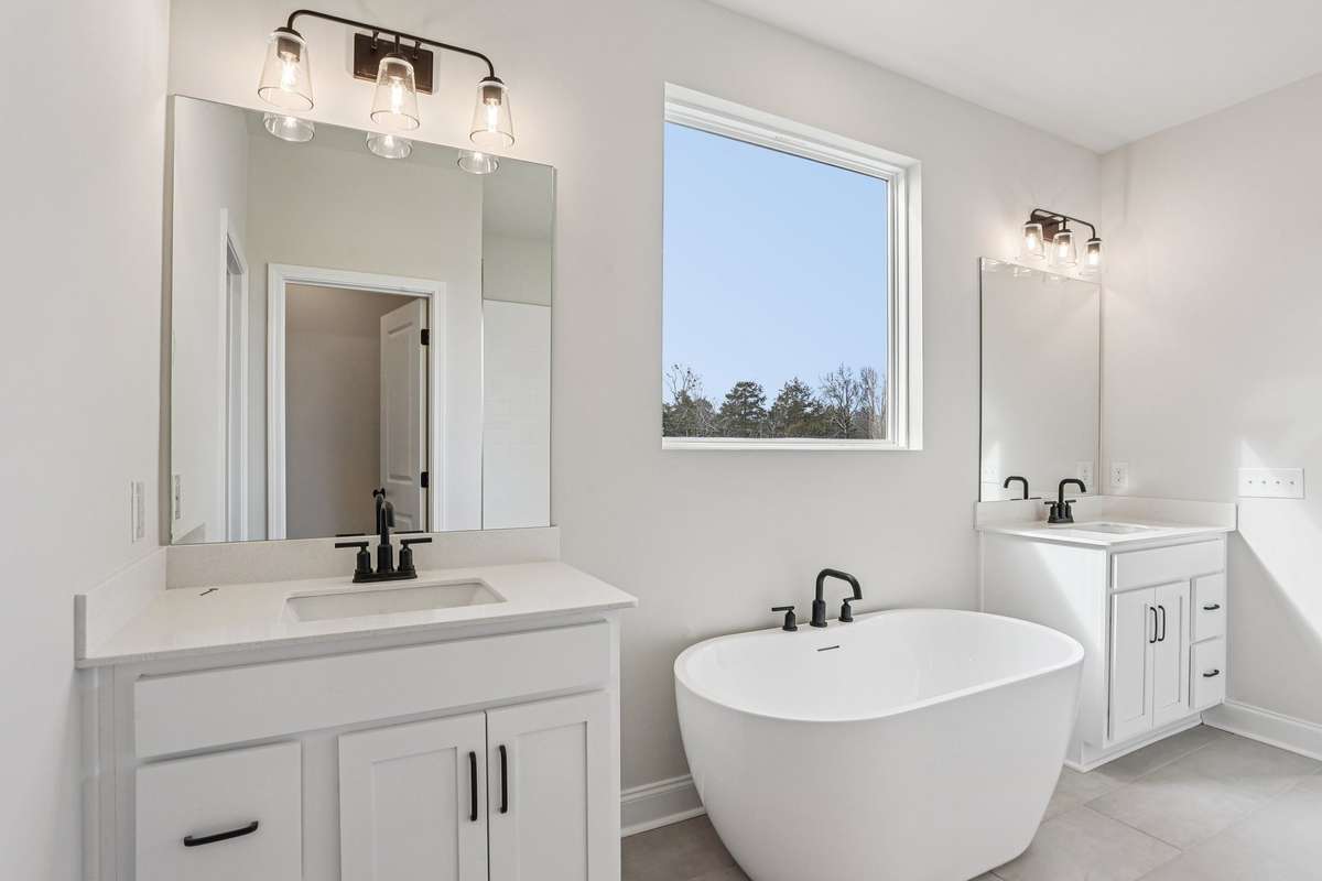 Relax and recharge in the freestanding soaking tub. Surrounded by tilework and positioned beneath a large window for natural light, this tub offers the perfect retreat for unwinding after a long day.