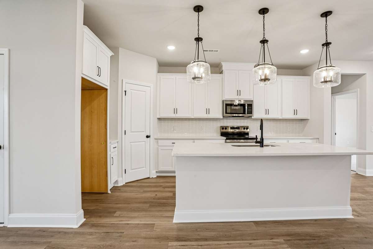 The island offers the perfect space for additional seating for quick meals. Pendant lighting also adds a designer touch to this beautiful kitchen.