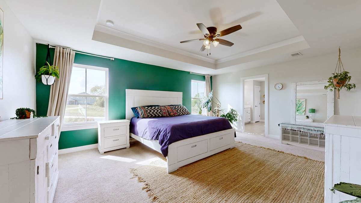 Spacious primary suite with tray ceiling, natural light and dual walk-in closets