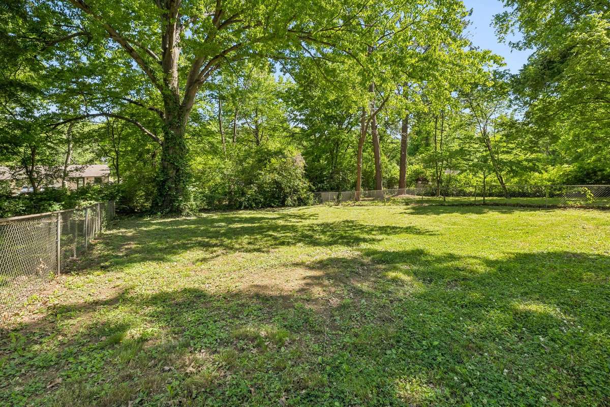 Massive fenced backyard with mature trees, plenty of space to play or entertain, and a built-in slide for added fun.