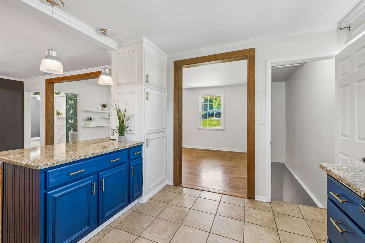Updated kitchen with granite countertops, two-tone cabinetry, and black appliances, filled with natural light.