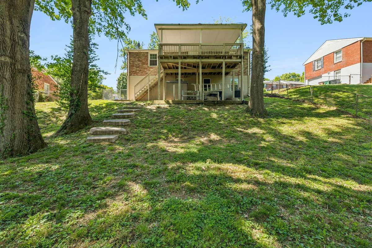 Massive fenced backyard with mature trees, plenty of space to play or entertain, and a built-in slide for added fun.