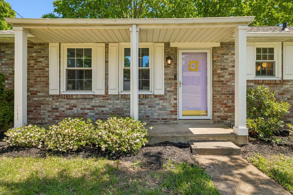 Welcoming covered front porch with charming entry—complete with a front door inspired by the iconic “Friends” design.