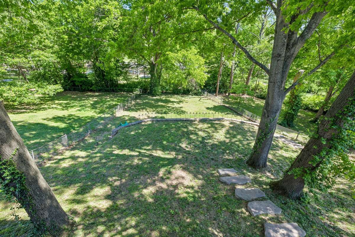 Massive fenced backyard with mature trees, plenty of space to play or entertain, and a built-in slide for added fun.
