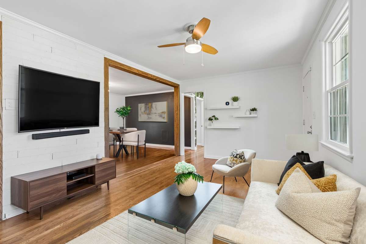 Spacious living room with abundant natural light and hardwood floors, offering plenty of room to relax or entertain. (virtually staged)