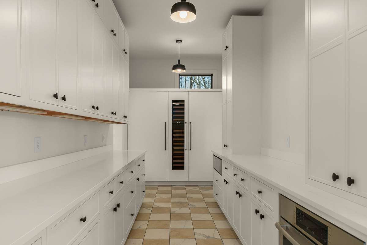 Scullery and secondary prep kitchen featuring extensive custom cabinetry, generous counter space, and built in wine storage, designed for seamless entertaining and everyday functionality.