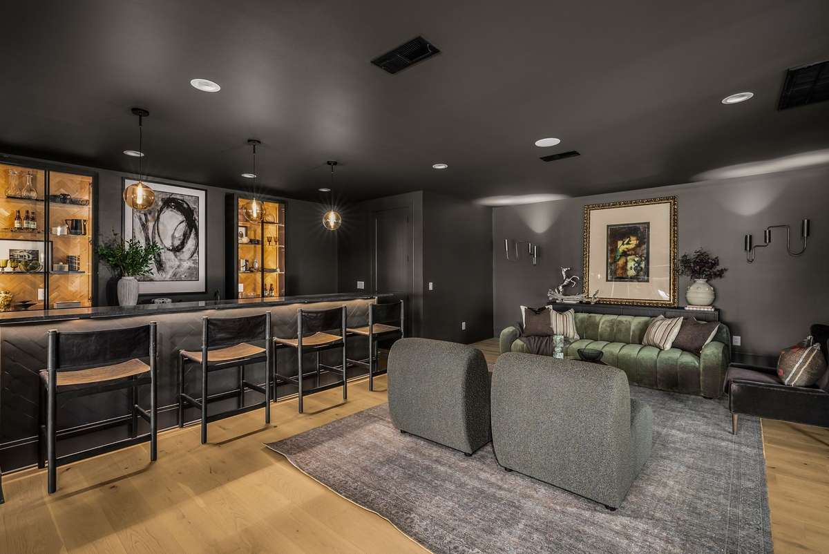 A custom wet bar anchors this intimate lower-level lounge with a refined, private club feel.