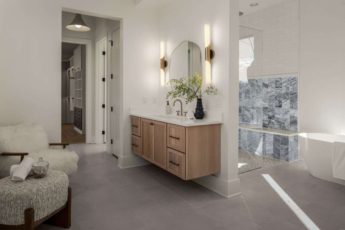 Another angle of the primary bath highlighting the custom floating vanity, sculptural lighting, and seamless flow into the shower and soaking tub for a true spa level experience.