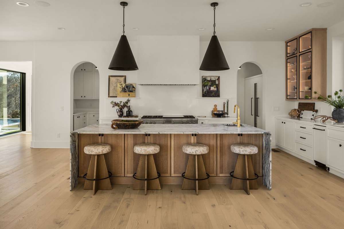 Open kitchen view featuring a spacious marble island with seating, custom cabinetry, and statement lighting, thoughtfully designed to anchor the main living spaces and elevate everyday gatherings.